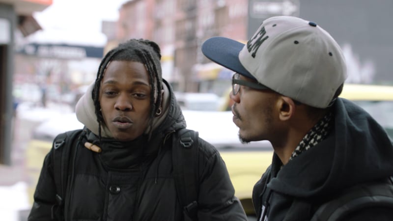 Two men are talking on a street corner.