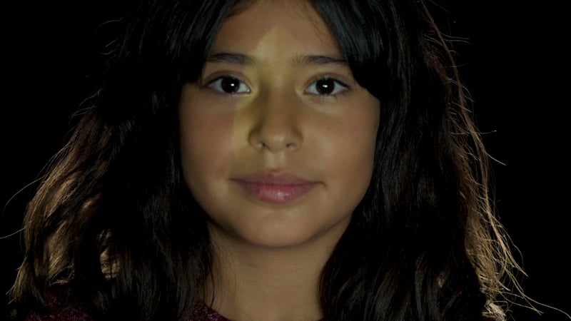 A young girl with long hair and a nose ring.